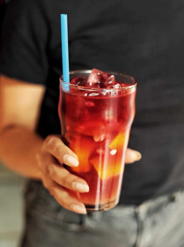Cocktail roșu cu gheață, servit la pahar înalt